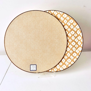 May include: Two round decorative plates. One plate has a tan dotted pattern with a brown border. The other plate has a white diamond pattern on a tan background with a brown border. The plates are from Holly Stuart Home.