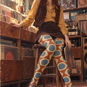 Peut inclure: Une chemise à manches longues boutonnée jaune moutarde, un gilet marron foncé, une mini-jupe en velours côtelé marron foncé et des collants à motifs géométriques répétitifs bleu, orange et crème, portés avec des chaussures Mary Jane marron.
