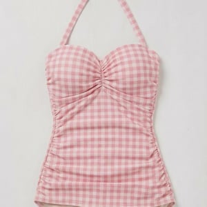 May include: A pink and white gingham swimsuit. The one-piece swimsuit has a halter neck tie, a sweetheart neckline, and ruching details. The bottom portion of the swimsuit is a solid light pink colour.