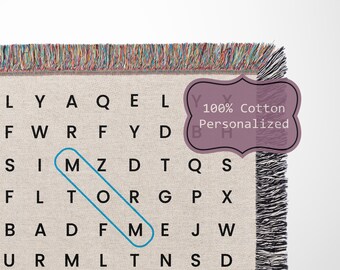May include: A woven throw blanket with a black and white word search pattern. The words are hidden in a grid of letters. The blanket has a fringe border and a label that says "100% Cotton Personalized".