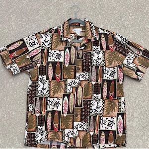 May include: Short-sleeved button-down shirt with a repeating pattern of surfboards, turtles, and geometric shapes in shades of brown, white, and red. The shirt is hanging on a hanger.
