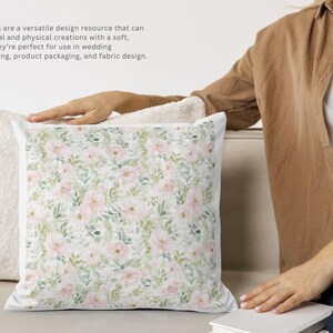 Pode incluir: Uma almofada decorativa com um padr&atilde;o floral de rosas cor-de-rosa e folhas verdes sobre um fundo branco. A almofada est&aacute; ao lado de uma almofada branca e fofa. A imagem inclui texto sobre padr&otilde;es sem costura para design.