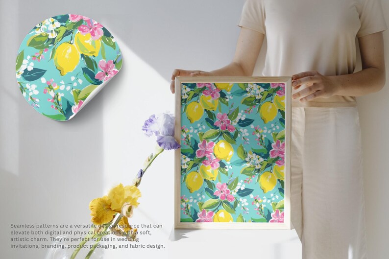 May include: A framed print and a sticker featuring a seamless pattern of yellow lemons, pink flowers, and green leaves on a turquoise background. The print is held by a person. The text reads: Seamless patterns are a versatile design resource.
