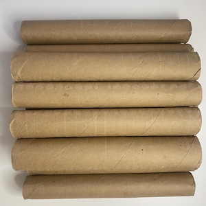 Peut inclure: Une pile de sept tubes en carton vides. Les tubes sont de couleur brun clair et semblent être faits de papier recyclé. Les tubes sont disposés horizontalement, avec les extrémités des tubes visibles.