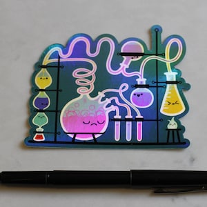 May include: A holographic sticker featuring a cartoon illustration of a science lab with beakers, flasks, and test tubes. The beakers and flasks have cute faces and are filled with colorful liquids. The sticker has a blue background with a holographic effect.