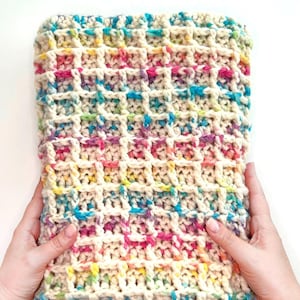 May include: A crocheted rectangular pillow with a waffle stitch pattern. The pillow is made with a multi-colored yarn with shades of pink, blue, yellow, and green.