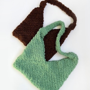 May include: Two fluffy, textured tote bags. One is a deep brown, the other is a soft green. Both bags have a triangular shape and a single shoulder strap. The bags are made of a soft, plush material.