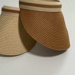 May include: Two straw sun visors, one beige and one brown, with a white stripe around the top.