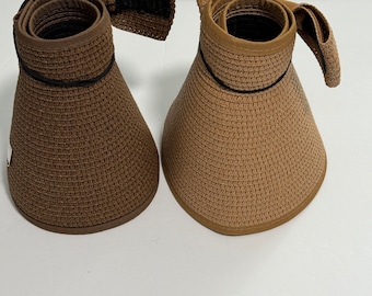 May include: Two brown straw sun hats with black trim. The hats have a wide brim and a chin strap.