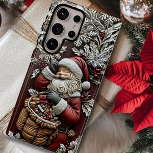 May include: A smartphone case featuring a festive Santa Claus design. The case is red and brown with a detailed illustration of Santa holding a sack of gifts. The case is resting on a wrapped gift box, surrounded by Christmas decorations.