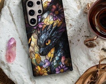 May include: A phone case with a dragon design, featuring a black and blue dragon with yellow eyes, set against a stained-glass style background. The flowers are purple, pink, and yellow. The case has a black border. The design is intricate and colourful.