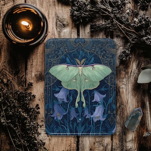 May include: A rectangular, dark blue decorative item featuring a large, light green Luna moth with purple accents, set against a backdrop of bluebell flowers. The design has a vintage, botanical aesthetic. The item is placed on a wooden surface.