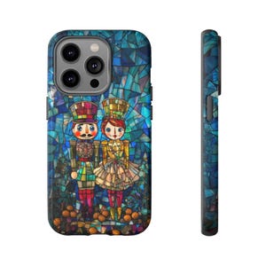 Op de afbeelding: Een telefoonhoesje met een kleurrijk glas-in-loodontwerp met twee notenkrakerfiguren. De hoes heeft een blauw, groen en bruin kleurenschema. De notenkrakers zijn gekleed in feestelijke kleding, met een gedetailleerd ontwerp. De hoes wordt van voren en van de zijkant getoond.