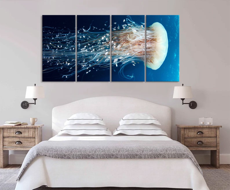Op de afbeelding: Een meerdelige wandkunstprint met een close-up van een kwal met lange, stromende tentakels tegen een blauwe achtergrond.
