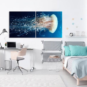 Op de afbeelding: Een gesplitst wandkunstwerk op canvas met een close-up van een kwal met lange, stromende tentakels in een blauwe oceaan. Het kunstwerk wordt getoond in een slaapkamer met een bureau, een stoel en een bed met een blauw-wit gepatroneerd hoofdeinde.