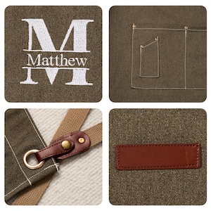 May include: An olive green apron with white embroidered lettering that reads "M Matthew M". The apron features a brown leather strap and a pocket. The fabric is a sturdy material.