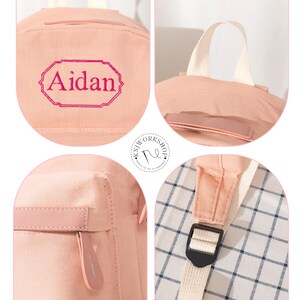 Puede incluir: Una mochila de color rosa claro con el nombre Aidan bordado en hilo rosa oscuro dentro de un borde decorativo. La bolsa incluye un asa superior, un bolsillo frontal con cremallera con tirador a juego y correas ajustables de color blanco roto.