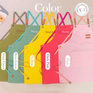 May include: A collection of colorful aprons in army green, bean green, yellow, dark pink, and pink. Each apron has a pocket and leather accents. The aprons are personalized with names and the word "Color" is at the top.