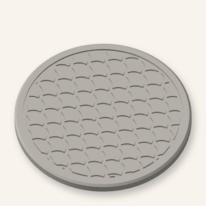 May include: A circular, light grey manhole cover featuring a repeating, embossed scale-like pattern across its surface. The design consists of interlocking, curved segments arranged in a grid, enclosed within a smooth, raised outer circular rim.