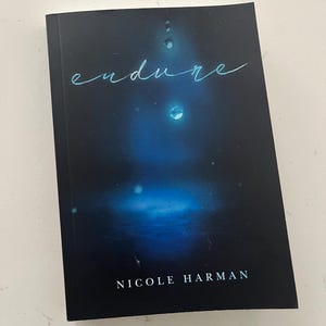 May include: A hardcover book with a dark blue cover featuring the word "endure" in a light blue script. The cover has a blurred blue and white design with water droplet accents. The author's name, Nicole Harman, is printed at the bottom.