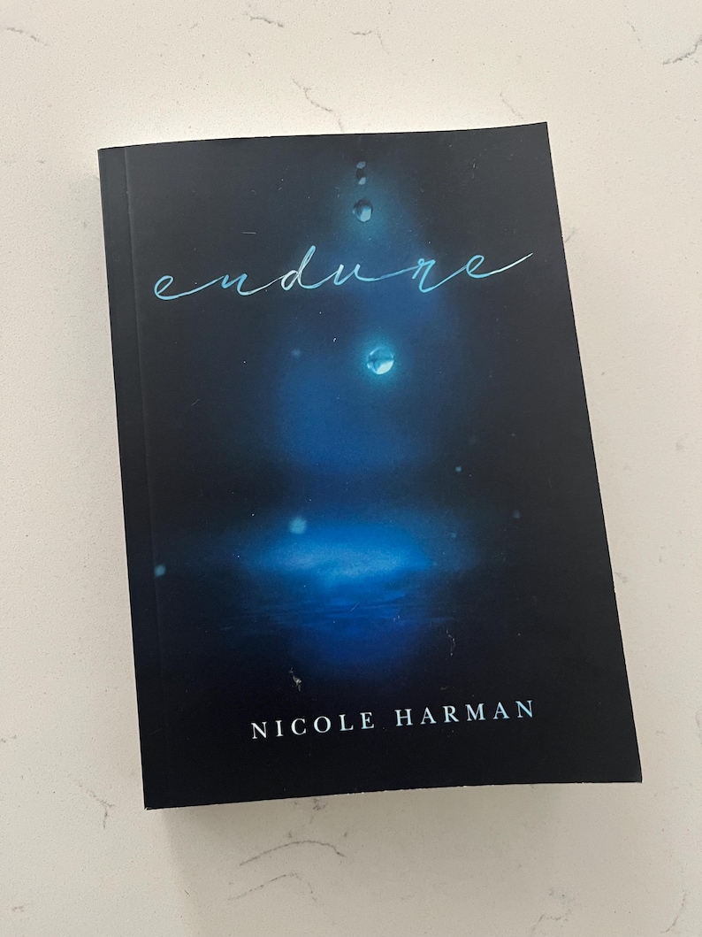 May include: A hardcover book with a dark blue cover featuring the word "endure" in a light blue script. The cover has a blurred blue and white design with water droplet accents. The author's name, Nicole Harman, is printed at the bottom.