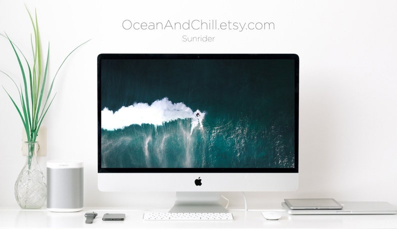 Puede incluir: Un ordenador de sobremesa blanco con una gran pantalla que muestra una vista a&eacute;rea de un surfista montando una ola en el oc&eacute;ano. El texto "OceanAndChill.etsy.com" y "Sunrider" se muestra encima de la pantalla.