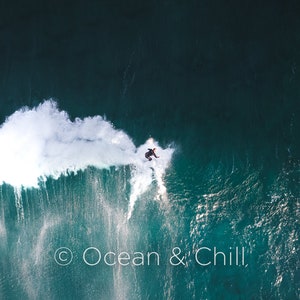 Puede incluir: Una vista a&eacute;rea de un surfista montando una ola en el oc&eacute;ano. La ola est&aacute; rompiendo y creando una cresta blanca y espumosa. El agua es de un color azul verdoso profundo. La imagen est&aacute; subtitulada "Ocean & Chill."