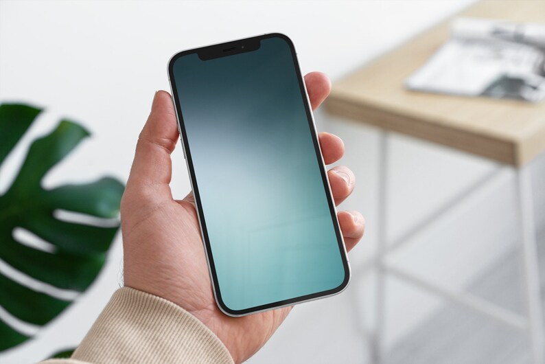 May include: A person holding a white smartphone with a black bezel and a gradient blue and green screen.