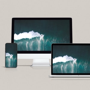 May include: A close-up of three devices displaying the same image of a large wave breaking in the ocean. The devices are a smartphone, a laptop, and a desktop computer.