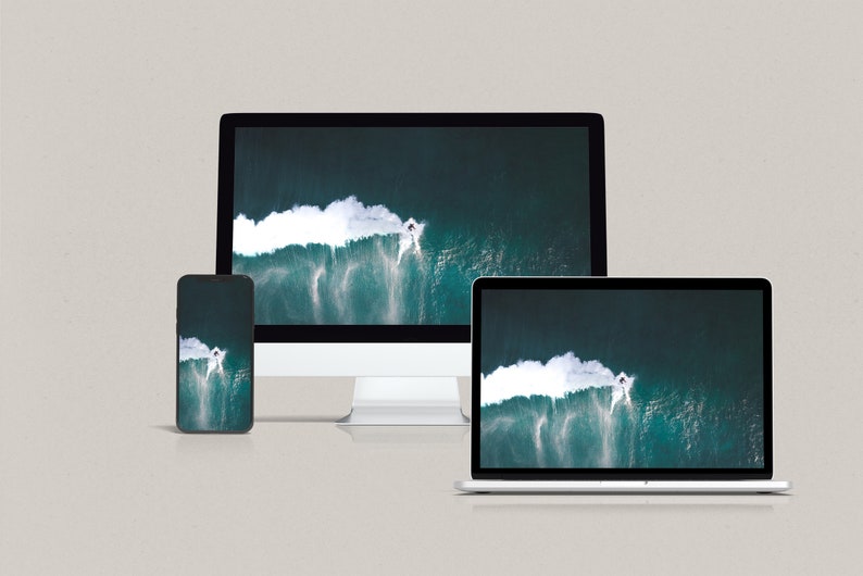 May include: A close-up of three devices displaying the same image of a large wave breaking in the ocean. The devices are a smartphone, a laptop, and a desktop computer.