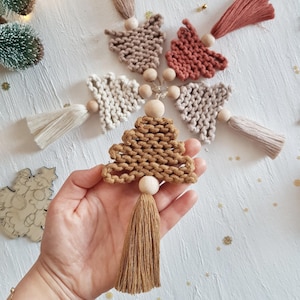 Può includere: Quattro decorazioni per l'albero di Natale in macramè fatte a mano con perline di legno e frange. Le decorazioni sono in tonalità di marrone, beige e rosa.