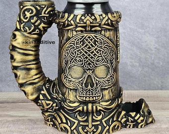 May include: A black and gold ceramic skull-shaped can holder with intricate designs. The holder is designed to fit a standard-sized can.