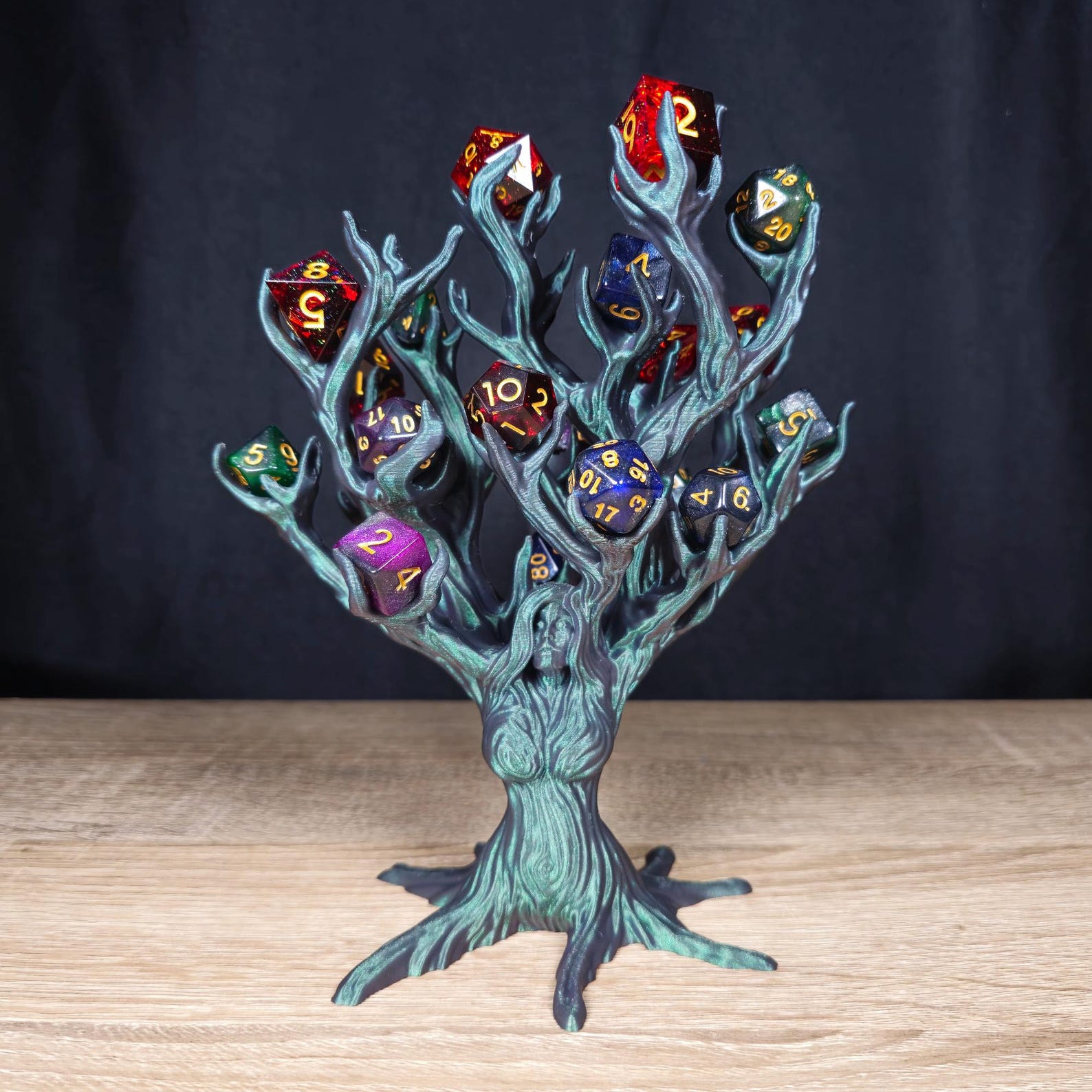 A grey and green iridescent tree goddess statue turns into branches where the hair/arms should be and the branches are holding DnD dice.