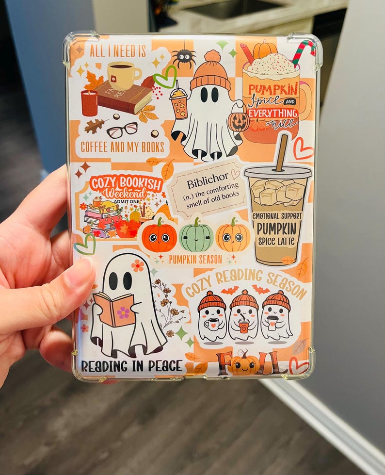 May include: A clear phone case with a fall-themed design. The case features illustrations of ghosts, pumpkins, coffee cups, books, and the text "All I Need Is Coffee and My Books", "Cozy Bookish Weekend", "Pumpkin Spice and Everything Nice", and "Reading in Peace".