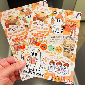 May include: Two fall-themed stickers with ghost illustrations, pumpkins, coffee, and the text "All I Need Is Coffee and My Books." One sticker reads "Cozy Bookish Weekend." The other says "Pumpkin Spice Latte."