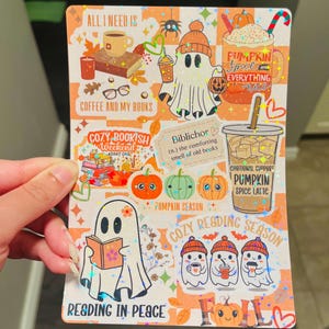 May include: A decorative sticker sheet with a fall theme. The sheet features illustrations of ghosts, pumpkins, coffee, books, and the text "Pumpkin Spice Everything Nice" and "Reading in Peace". The background is orange and white.