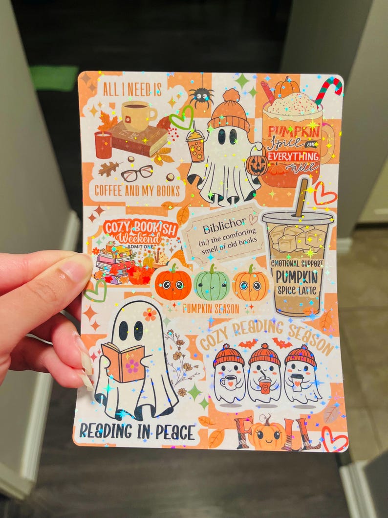 May include: A decorative sticker sheet with a fall theme. The sheet features illustrations of ghosts, pumpkins, coffee, books, and the text "Pumpkin Spice Everything Nice" and "Reading in Peace". The background is orange and white.