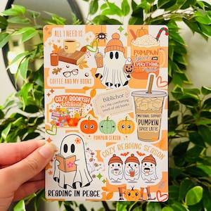 May include: A rectangular sticker sheet with a fall theme. The design features ghost illustrations, pumpkins, coffee cups, and text like "Pumpkin Spice" and "Cozy Reading Season." The background has an orange and white checkered pattern.
