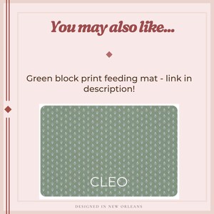 Puede incluir: Una alfombra de alimentaci&oacute;n verde con estampado de bloques blancos y el nombre "CLEO" en texto blanco. La alfombra es rectangular con esquinas redondeadas. El texto "You may also like..." est&aacute; en la parte superior y "DESIGNED IN NEW ORLEANS" en la inferior.