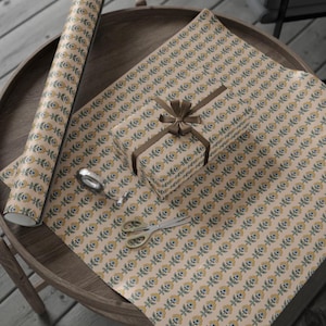 May include: Gift wrapping paper with a repeating floral pattern in yellow, blue, and green on a beige background. A wrapped gift with a brown ribbon and bow sits on the paper. A roll of paper, scissors, and tape are also visible.