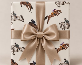 May include: A rectangular gift box wrapped in cream-colored paper featuring a repeating pattern of horses and riders in various equestrian poses. The package is tied with a wide, smooth, metallic gold satin ribbon finished in a large bow.