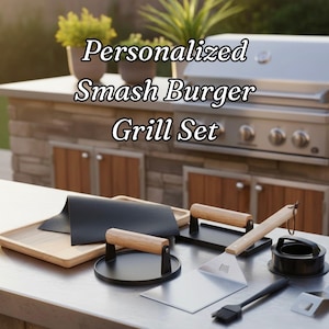 May include: A selection of barbecue tools, including a spatula, burger press, and a brush, arranged on a stainless steel surface. The text "Personalized Smash Burger Grill Set" is displayed above the tools. A grill is in the background.