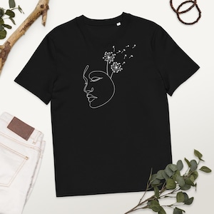 May include: Black t-shirt with a white line drawing of a face with dandelion seeds blowing from the top of the head.