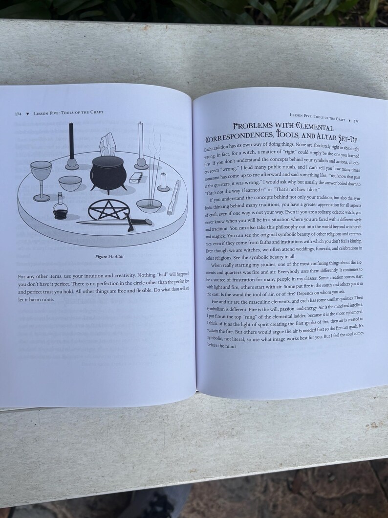 Pode incluir: Um livro aberto com um diagrama de uma configura&ccedil;&atilde;o de altar, incluindo um caldeir&atilde;o, c&aacute;lices, velas e um pentagrama. O texto discute correspond&ecirc;ncias elementais e ferramentas para pr&aacute;ticas de bruxaria.