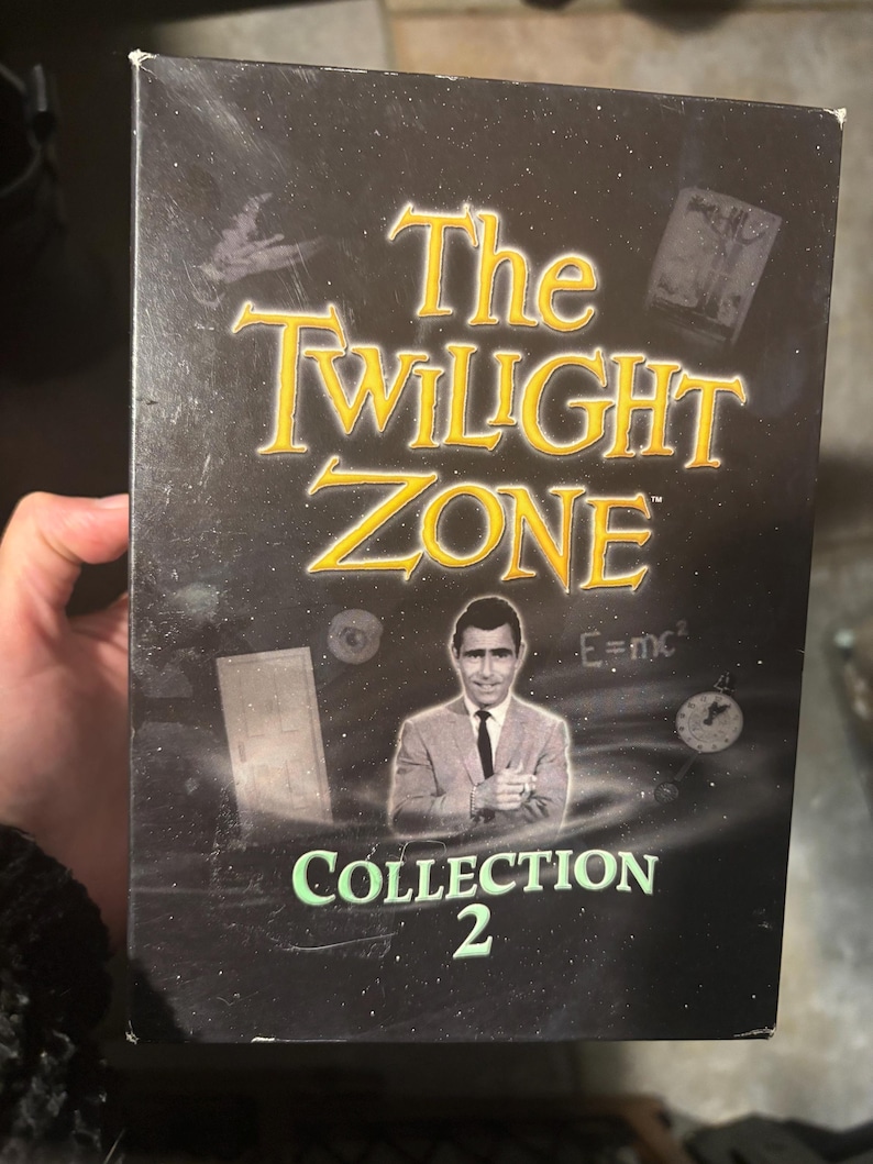 May include: A black DVD box with a green and white title "The Twilight Zone Collection 2". The box features a black and white image of Rod Serling, the show's creator, against a dark background with various images and text.