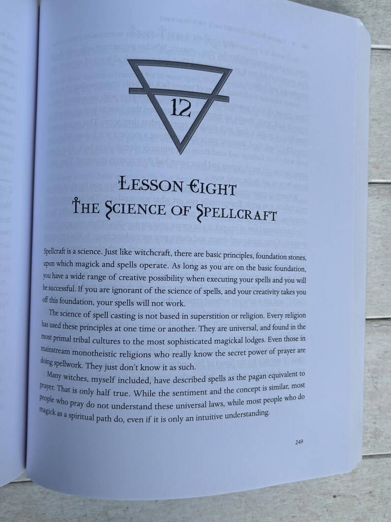 Pode incluir: P&aacute;gina de livro aberta com texto e um s&iacute;mbolo. O t&iacute;tulo "Lesson Eight" &eacute; seguido por "The Science of Spellcraft". Um tri&acirc;ngulo com uma linha e o n&uacute;mero 12 est&aacute; no topo. O texto discute feiti&ccedil;os e bruxaria.