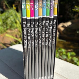 May include: A set of eight DVD cases for The Twilight Zone, volumes 10 through 18. The cases are black with a silver spine and feature a colorful design with the volume number and show title.