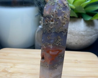 May include: A tall, pointed, gray, white, and orange agate crystal with a rough, textured surface.