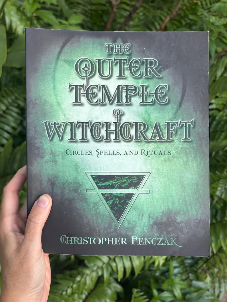 Pode incluir: Um livro intitulado "The Outer Temple of Witchcraft" com uma capa verde e preta. A capa apresenta o t&iacute;tulo em letras grandes e ornamentadas, com o nome do autor, Christopher Penczak, na parte inferior. O subt&iacute;tulo do livro &eacute; "C&iacute;rculos, Feiti&ccedil;os e Rituais."