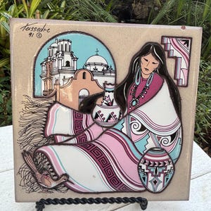 May include: A ceramic tile with a painted image of a woman in a colorful shawl, holding a pot. The background features a church with a blue sky. The tile is signed "Tussedrc 91" in the top left corner.